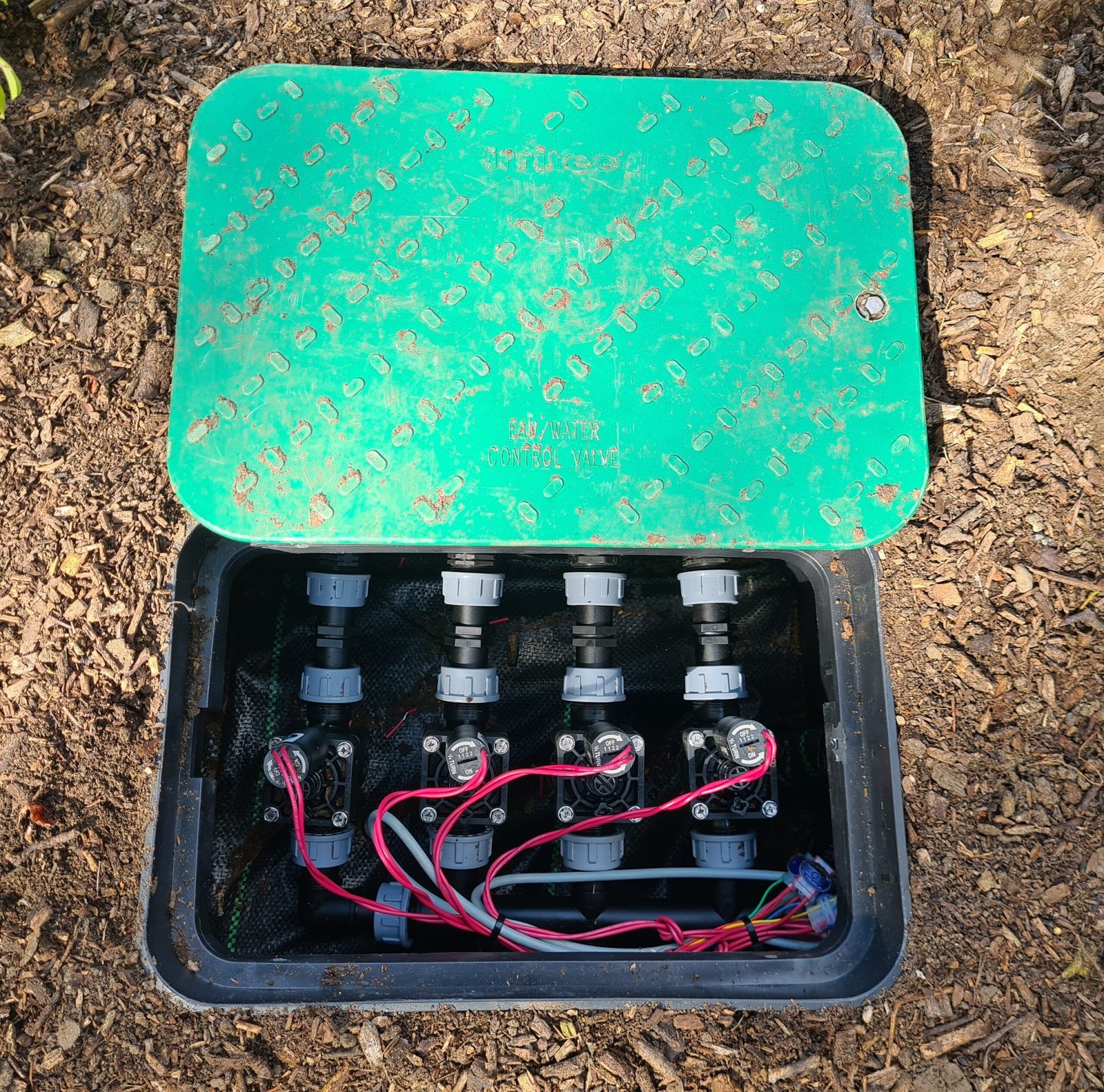 valve box sunk in the soil with solenoids